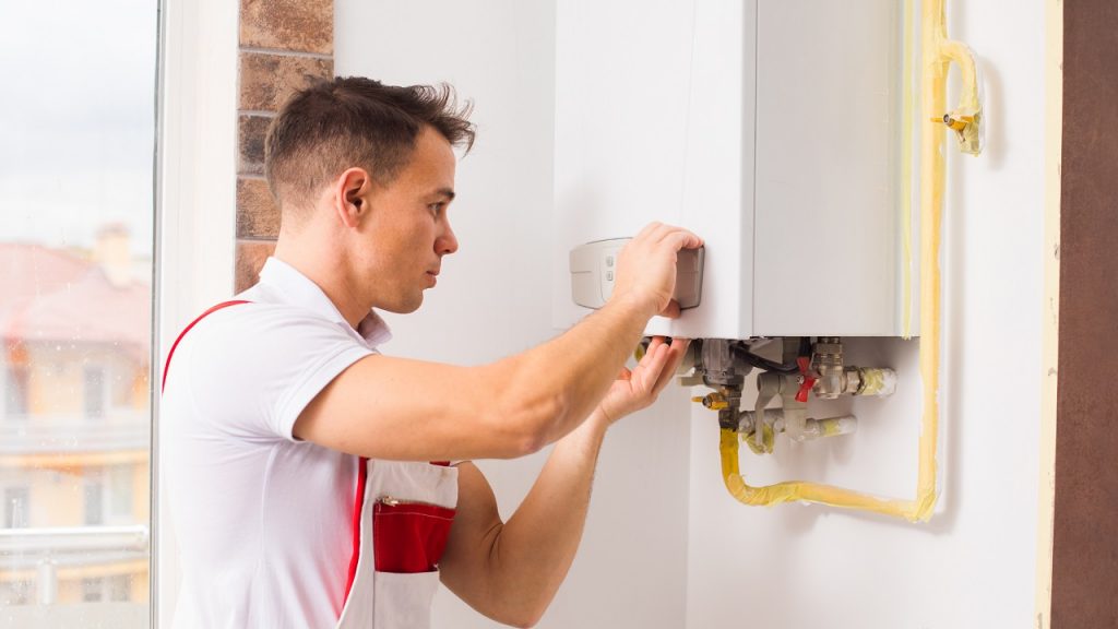 The plumber repairs a boiler at the kitchen